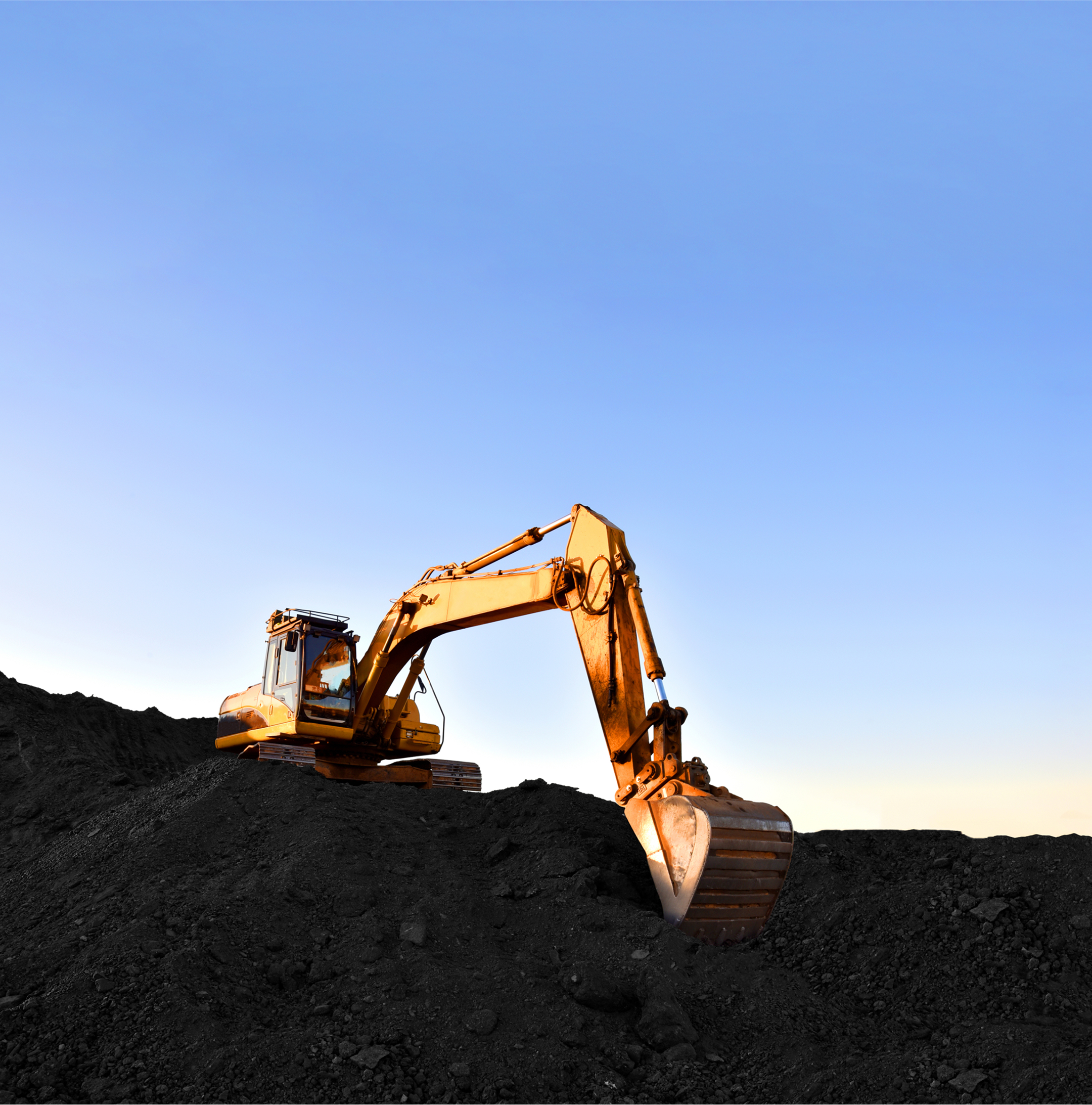 A yellow excavator parked at sunset, representing heavy equipment ready for its October winterization and maintenance checklist to ensure a profitable 2026.